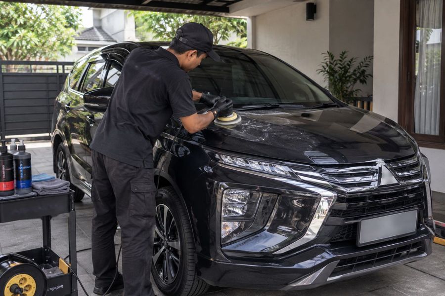 Teknisi memoles body mobil di garasi rumah pelanggan